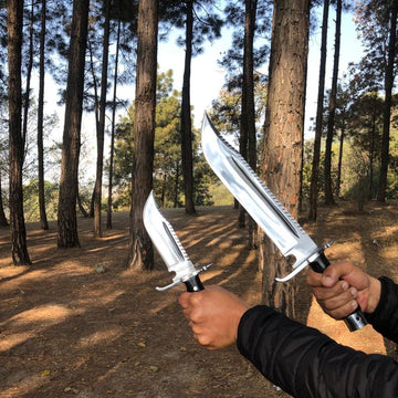 Two people holding large knives in a forest setting